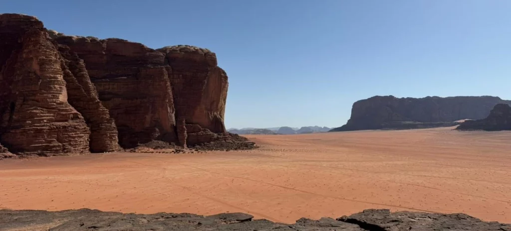 Paisagem do deserto Wadi Rum com a areia vermelha e os promontórios ao fundo